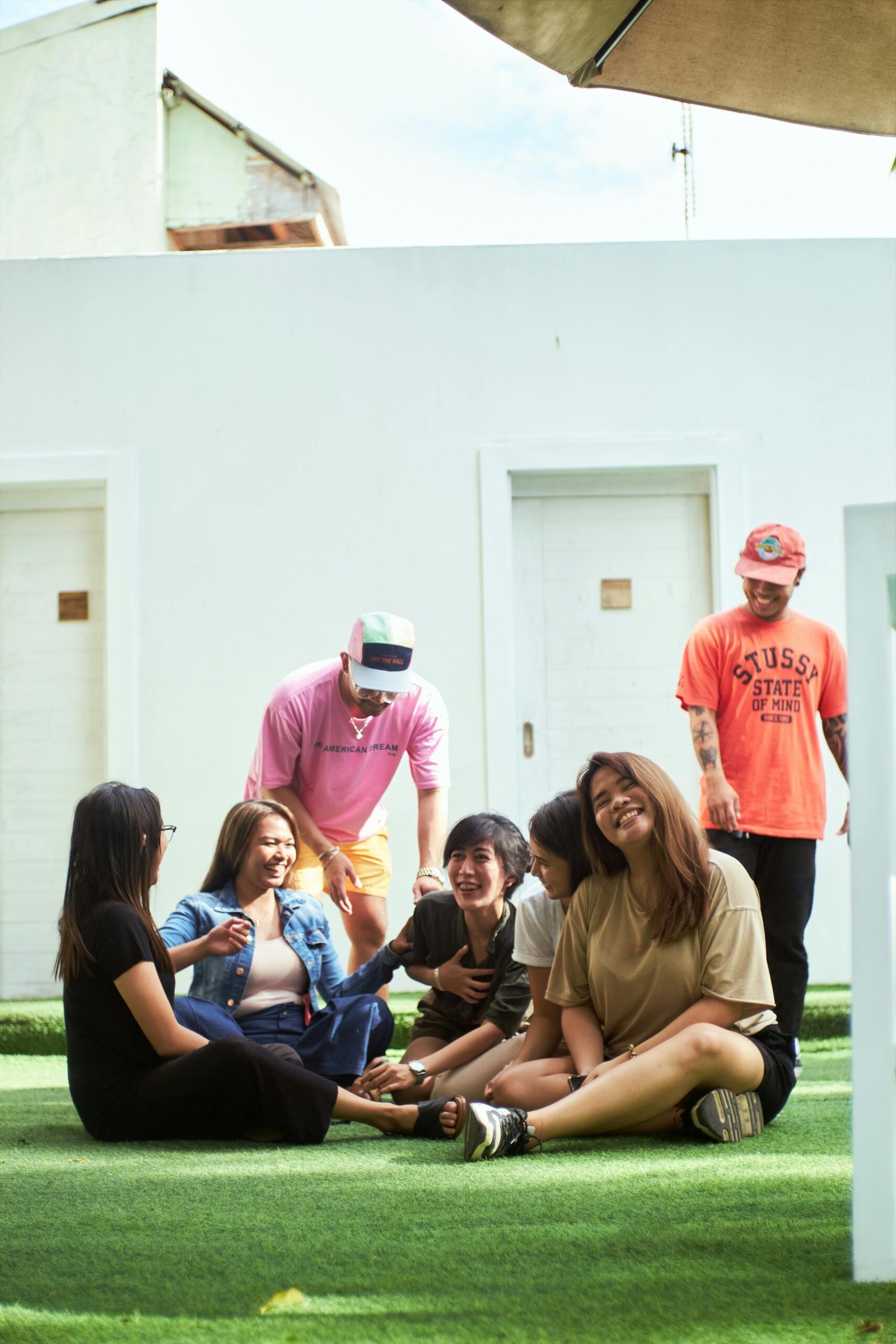 A joyful group of friends laughing and enjoying leisure time outdoors on a sunny day.
